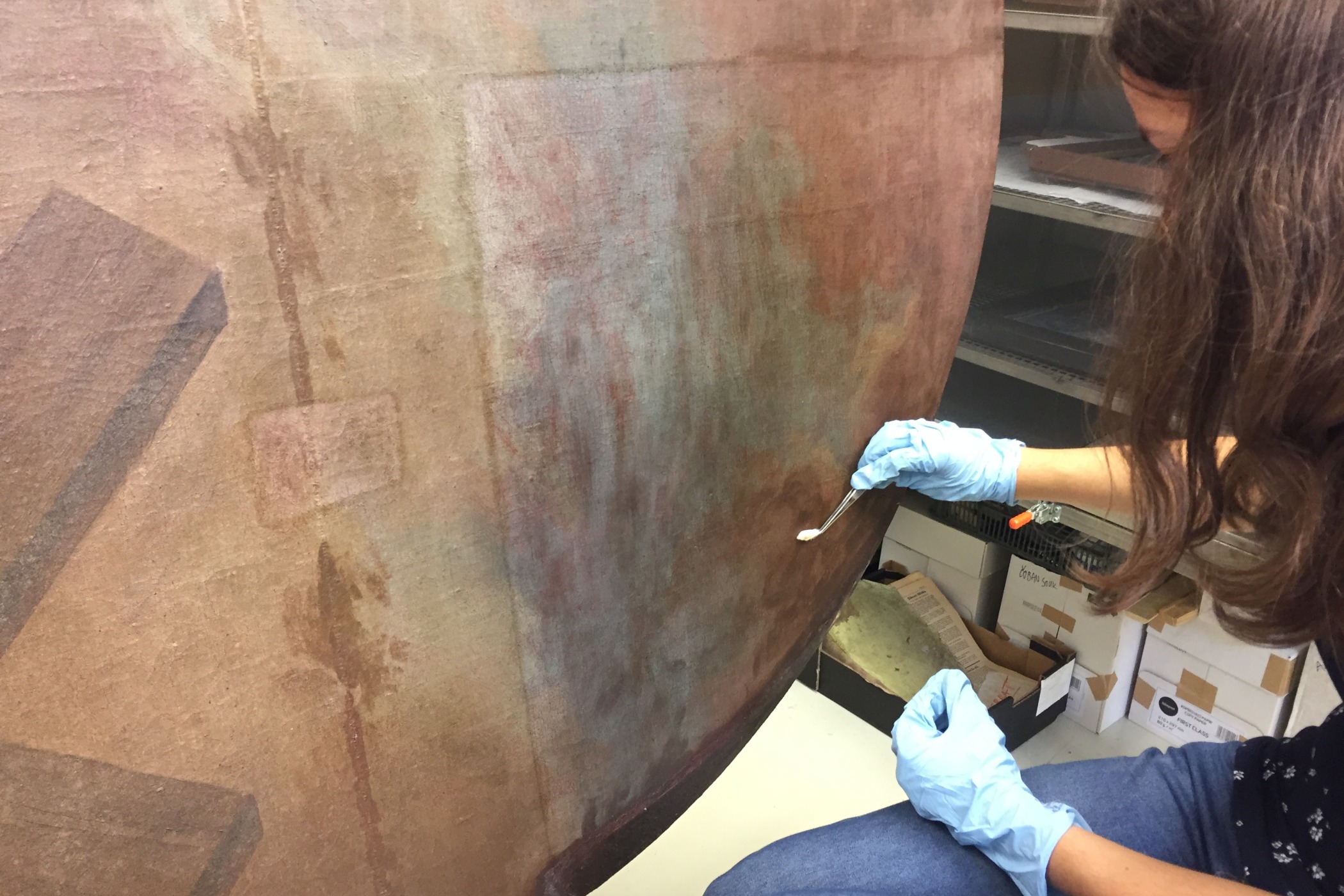 Jedna ze studentek Fakulty restaurování si na pinzetu namotává vatový tampón, namáčí ho v rozpouštědle a pak ho jemně nanáší na obraz.