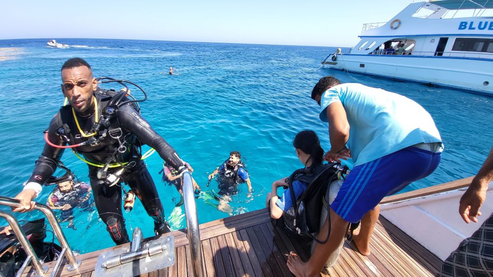 Egyptská posádka lodi pomáhá potápěčům sundávat ze zad lahve a zouvat ploutve