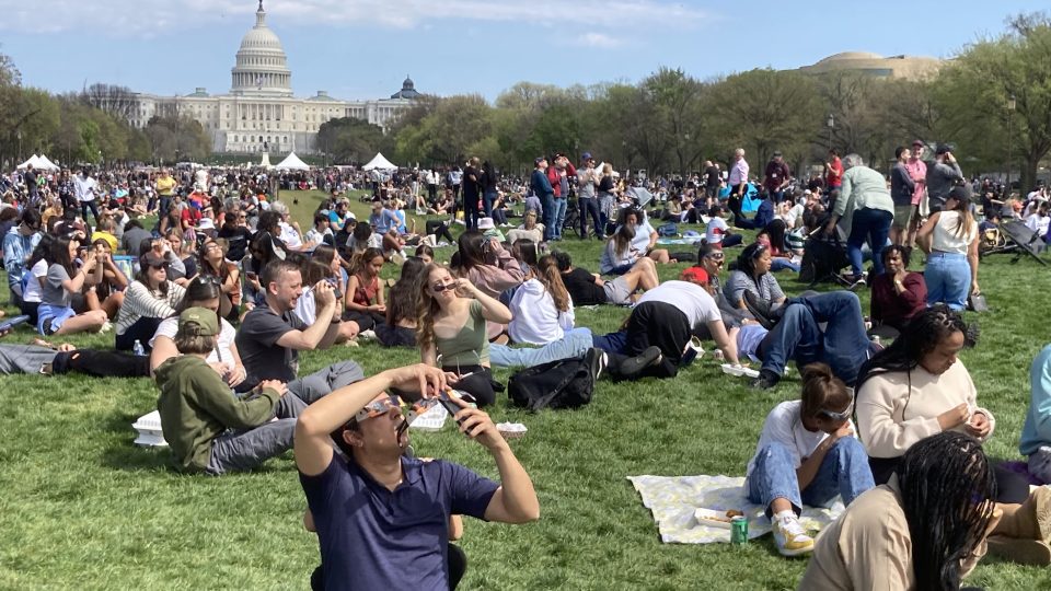 Obyvatelé Washingtonu pozorují částečné zatmění Slunce v parku National Mall