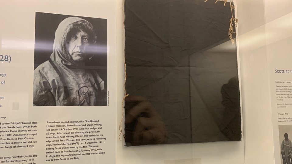 Roald Amundsen na dobové fotografii, hned vedle kusu černého praporu, který zanechal na jižním pólu