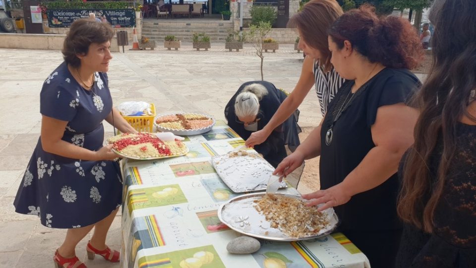 Místní ženy rozdávají před kostelem pečené jidáše a do malých papírových sáčků sypou oříšky a zrníčka z granátových jablek