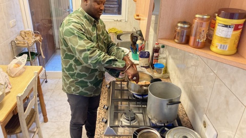 Amedu, povoláním zámečník a voják z Gambie, připravuje pro celé společenství smažené kuře s omáčkou z burákového másla a rýži