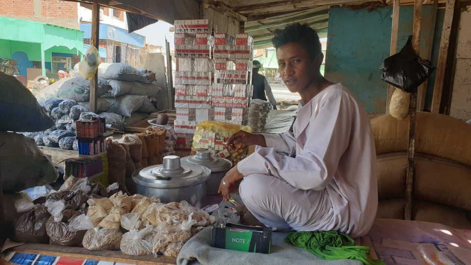 Tržiště v Šaátínu: mladý prodavač tady sedí přímo na pultě v dlouhé košili