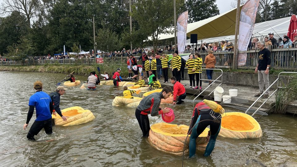 Mladí muži v neoprenech asistují závodníkům přímo ve vodě