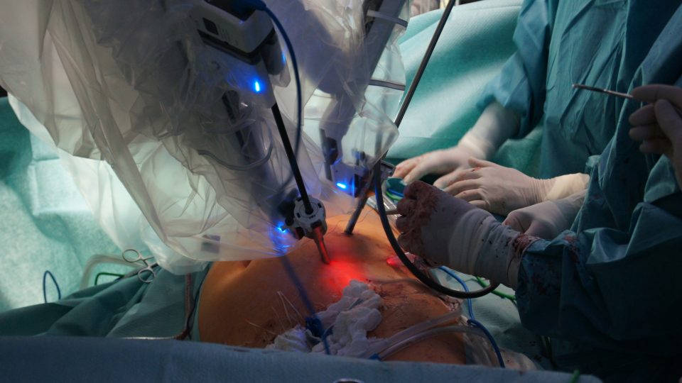 Robotická ramena s chirurgickými nástroji zavedenými do těla pacienta