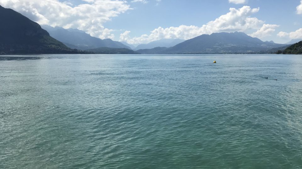 Jezero s průzračnou vodou rámují siluety Savojských Alp