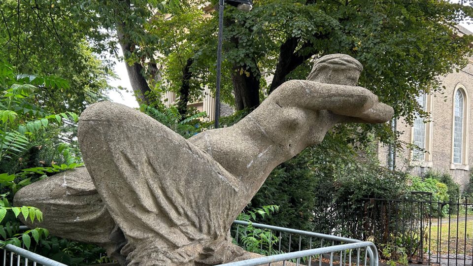Nadrozměrná socha ženy leží na levém boku a vypadá to, jako by postava levitovala