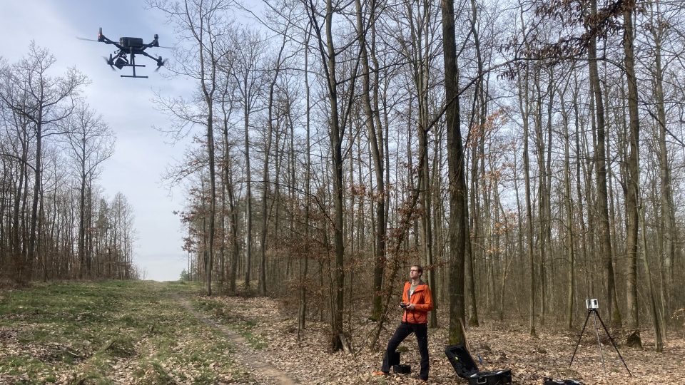 Martin Krůček s dronem skenuje les. Vpravo pozemní skener, vlevo dron