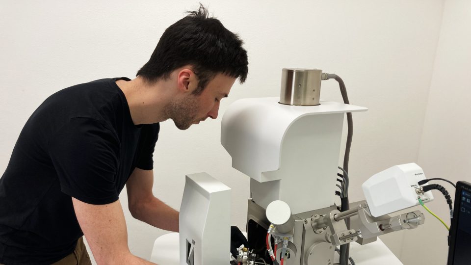 Michał Płygawko vkládá gombík do elektronového mikroskopu