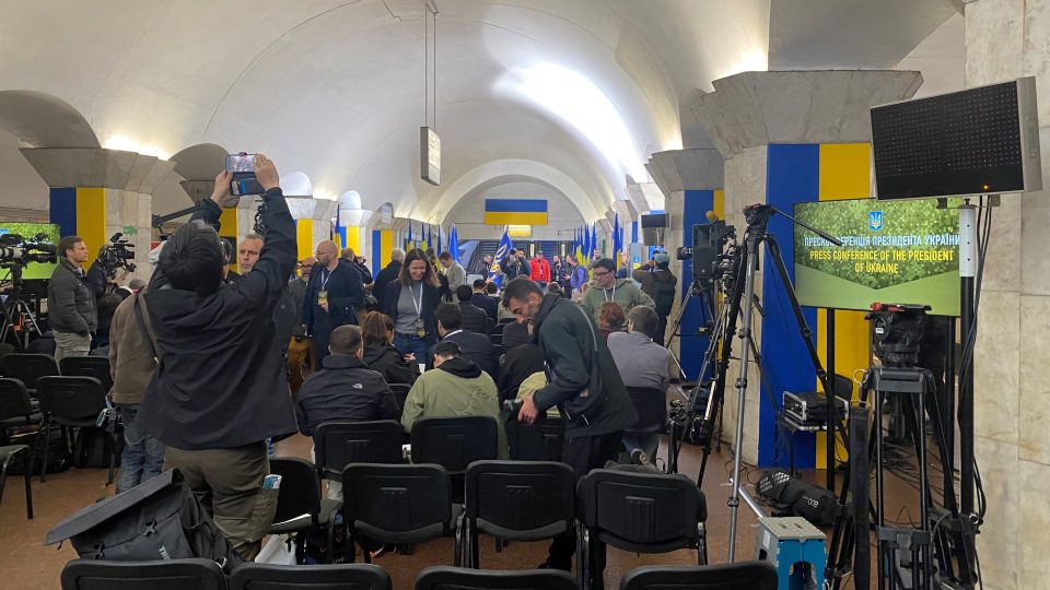 Novináři se shromáždili v jedné ze stanic kyjevského metra. Prezident Zelenskyj seděl na stupínku obklopený ukrajinskými vlajkami