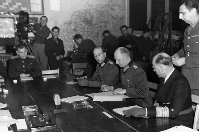 Generál Alfred Jodl v Remeši podepisuje bezpodmínečnou kapitulaci německých vojsk  (po jeho levé ruce je generál admirál von Friedeburg,  vpravo pak major Wilhelm Oxenius) | foto: Národní archiv USA