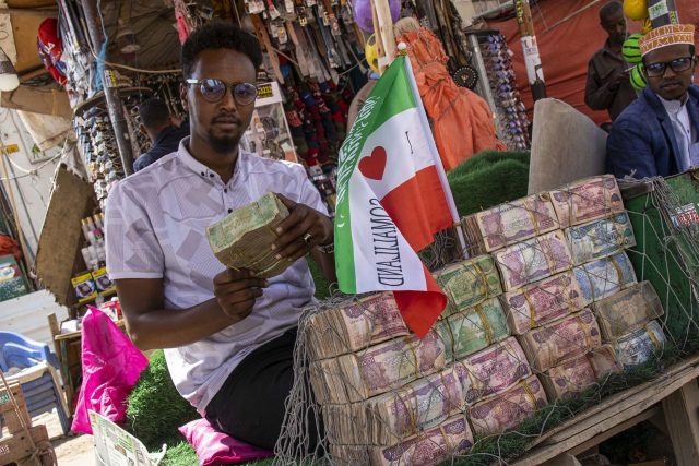 Na vršku své zídky z balíků bankovek má stojánek se somalilandskou vlajkou | foto: Kateřina Havlíková,  Český rozhlas