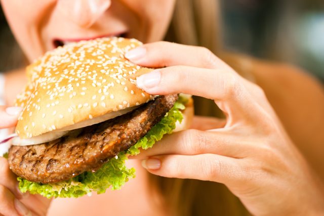 Hamburger,  žena jí burger,  kouše do hamburgeru | foto: Profimedia