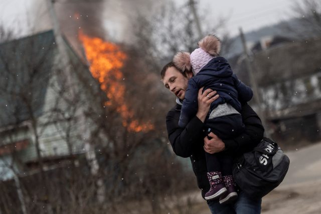 Muž s dítětem po těžkém ostřelování unikají z města Irpiň po jediné únikové cestě používané místními obyvateli,  zatímco ruské jednotky postupují směrem k hlavnímu městu Kyjev | foto: Reuters