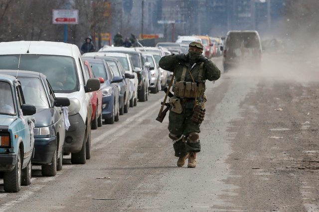 Příslušník proruských jednotek prochází podél řady aut s evakuovanými,  kteří opouštějí obležené jihoukrajinské přístavní město Mariupol | foto: Reuters