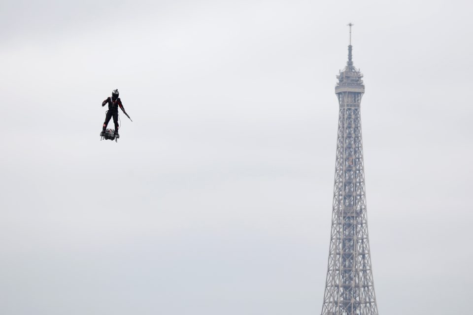 Přehlídku doplnil „létající muž“ na futuristickém zařízení zvaném Flyboard Air. Je to zvláštní vznášedlo podobné dronu a vybavené podle AFP několika motory. Pilot na zařízení během letu stojí | foto: Charles Platiau,  Reuters