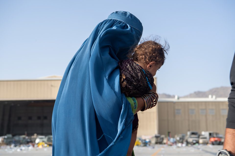 Žena nese dítě na palubu amerického letadla při evakuaci z kábulského letiště | foto: Reuters